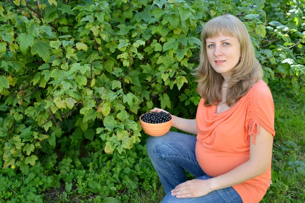 Těhotná žena s miskou bobulí černého rybízu v g — Stock fotografie