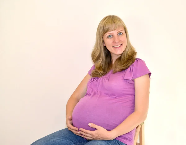 Η νεαρή έγκυο γυναίκα που κάθεται σε μια καρέκλα — Φωτογραφία Αρχείου