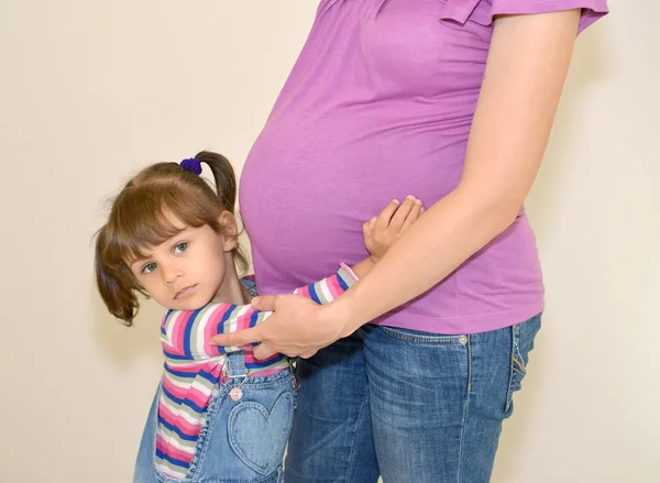 Eller hamile anne küçük kız kucaklar — Stok fotoğraf