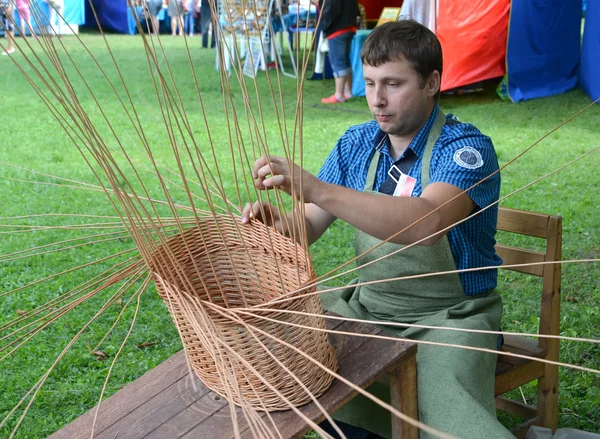 O handicraftsman gira uma cesta de uma vara na feira do nacional — Fotografia de Stock