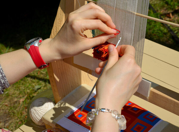 Руки женщины, работающей на крошечном ткацком станке. Ярмарка ната
