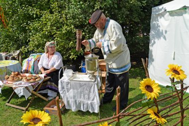 The elderly man kindles a samovar at fair of national creativity clipart