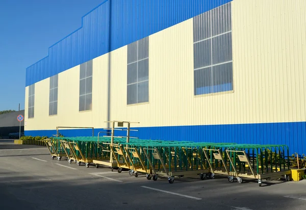 Cargo carts stand near the building of modern plant — Stock Photo, Image