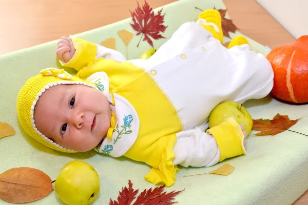 El bebé alegre se encuentra entre las hojas de otoño y la fruta — Foto de Stock