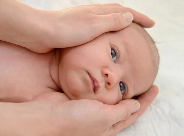 As mãos da mãe abraçam a cabeça do bebê — Fotografia de Stock