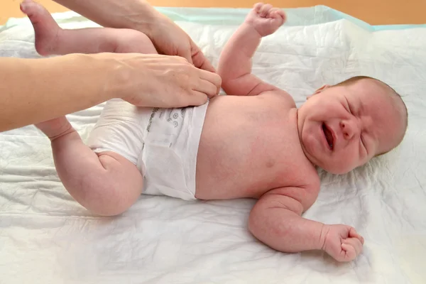 De vrouw jurken een luier aan de huilende baby — Stockfoto