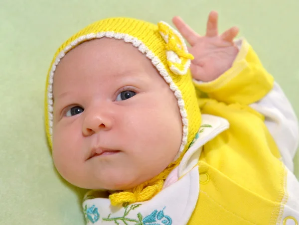 The baby's portrait in a yellow cap on a green background — Stock Photo, Image