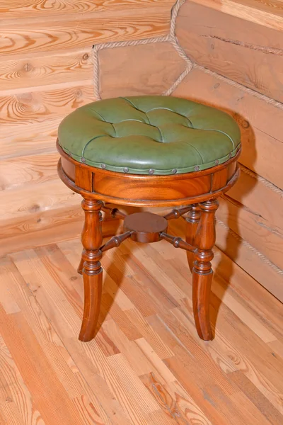 The stool with a leather upholstery stands near a timbered wall — Stock Photo, Image