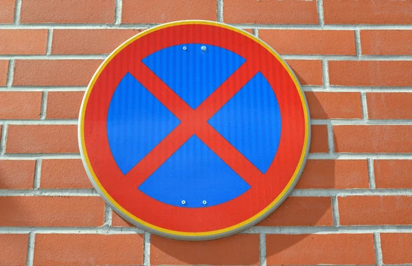 Дорожный знак "Остановка запрещена" закреплен на красной кирпичной стене — стоковое фото
