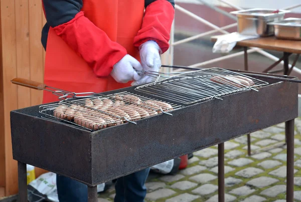 The man fries sausages on a street brazier — Stock Photo, Image