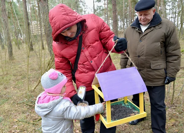 The young man with the daughter and the grandfather put grains i — Stock Photo, Image