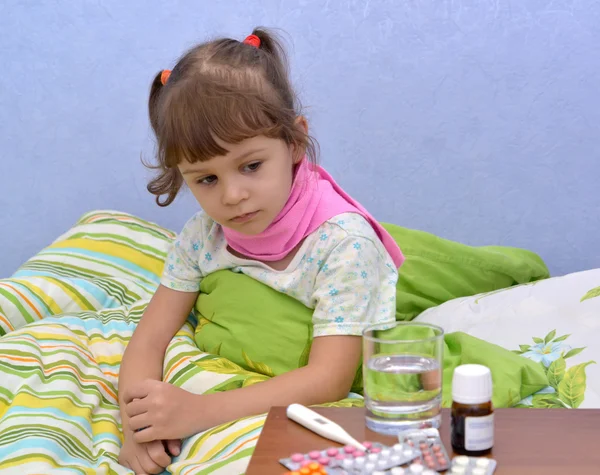 Portrait de la petite fille malade assise dans un lit près de la drogue — Photo