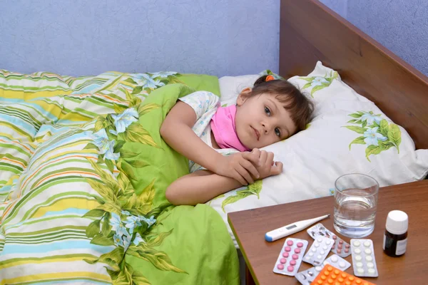 La petite fille malade triste se trouve dans un lit — Photo