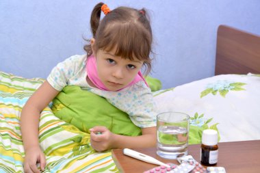Uyuşturucu yakınındaki bir yatakta oturan küçük hasta kız portresi