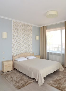 Bir çift otel odasında bir çift kişilik yatak ile hafif tonları iç