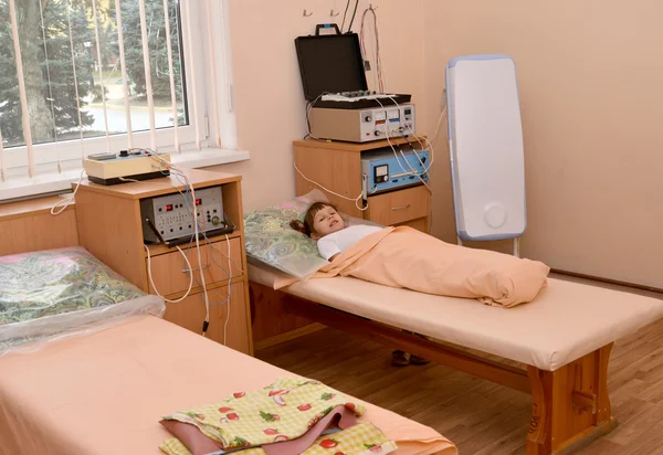 Mała dziewczynka chory leży na kanapie w terapii biorezonansowej ofi — Zdjęcie stockowe