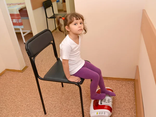 La petite fille reçoit la procédure sur un masseur à rouleaux. Bureau o — Photo