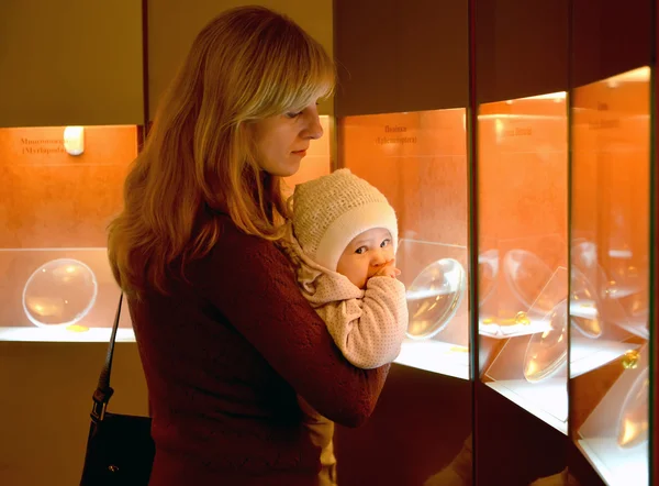 La jeune femme avec le bébé envisager des expositions ambre dans le mus — Photo