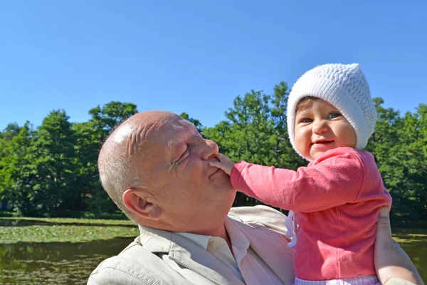 Літня людина тримає на руках маленьку онучку в парку — стокове фото