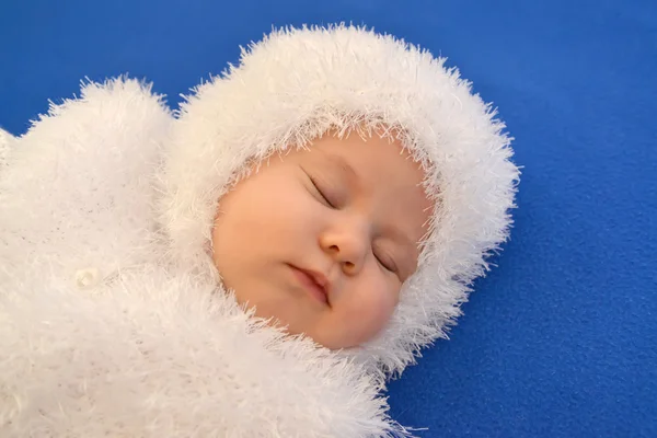 O bebê adormecido no terno de um Ano Novo do Floco de Neve em um fundo azul, um retrato — Fotografia de Stock