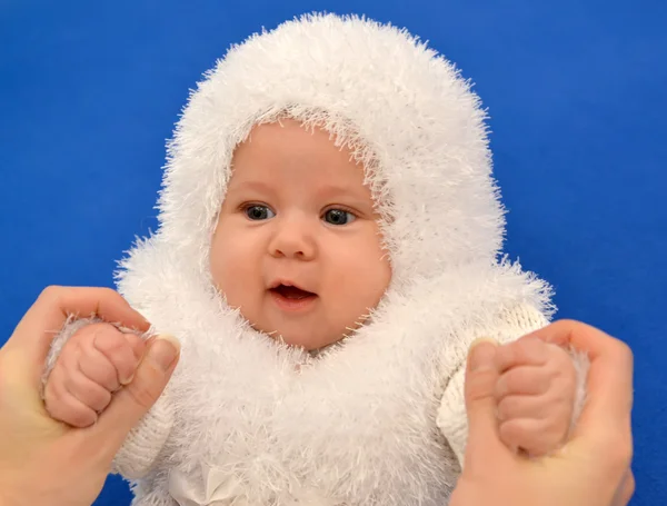 Frauenhände halten das Baby im Neujahrsanzug der Schneeflocke auf blauem Hintergrund — Stockfoto