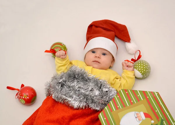 El bebé en un traje de Año Nuevo de Santa Claus con decoraciones de árboles de Navidad sobre un fondo claro — Foto de Stock