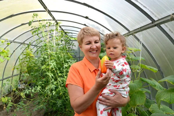 The woman gives to the little granddaughter sweet paprika in the — Stock Photo, Image