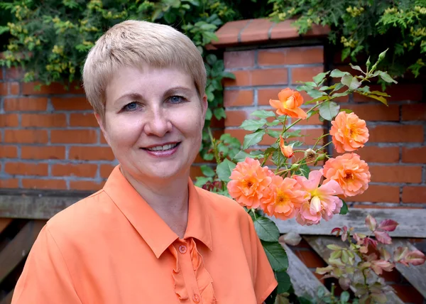 Portrait de la femme joyeuse des années moyennes avec des roses contre — Photo