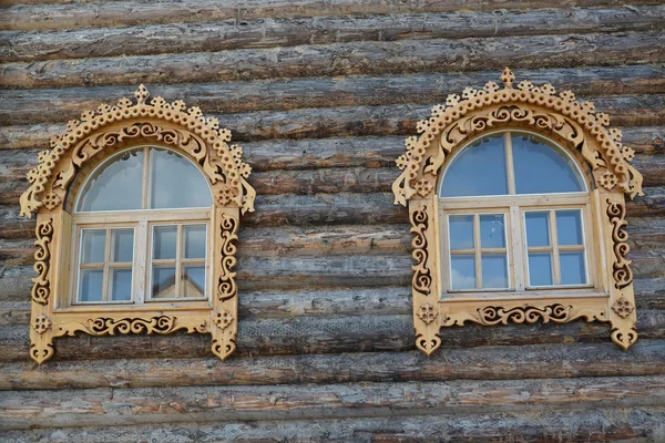 Two windows with wooden carved platbands on a timbered wall — Stock Photo, Image