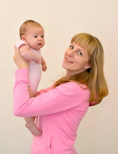 The happy young woman lifts on hands of the baby — Zdjęcie stockowe