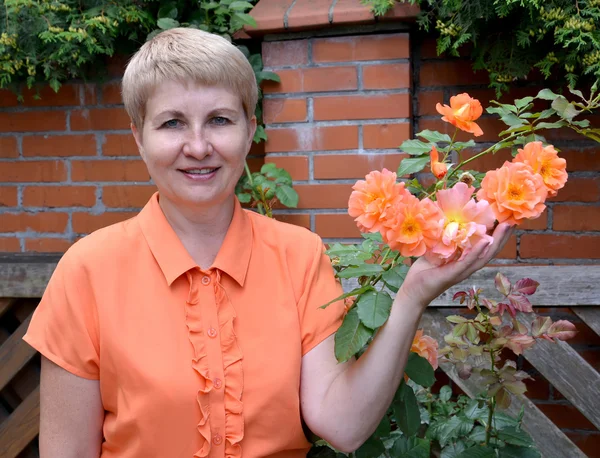 Веселая женщина средних лет показывает руку розы в гарде — стоковое фото