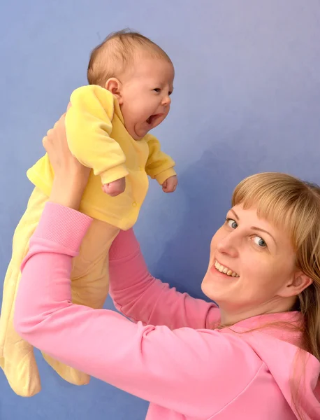 A jovem levanta-se nas mãos do bebê — Fotografia de Stock