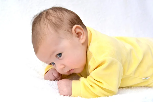 Das Baby liegt auf dem Bauch. ein Porträt auf hellem Hintergrund — Stockfoto