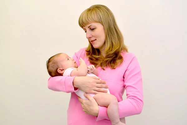 Die glückliche junge Frau hält das Baby an den Händen — Stockfoto