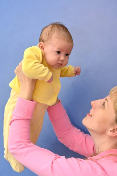 Die junge Frau hebt die Hände des Babys — Stockfoto