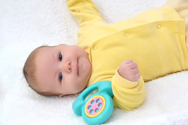 Il bambino si trova con il telefono giocattolo su uno sfondo bianco — Foto Stock