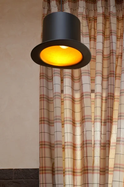 Die Lampe in Form eines schwarzen Zylinders gegen karierte Säulenhallen — Stockfoto