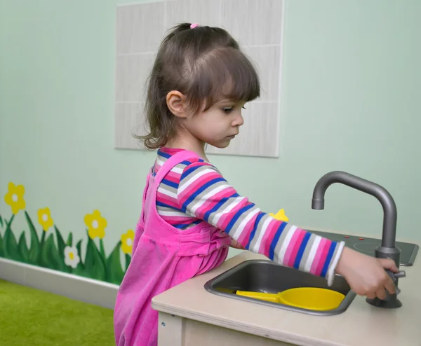 Маленька дівчинка грає на дитячій кухні. Дитячий садок — стокове фото