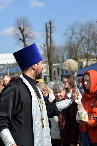 КАЛИНИНГРАД, РОССИЯ - 11 апреля 2015 года: Православный священник освящает верующих и пасхальные торты с помощью аспергиллума. Пасха — стоковое фото