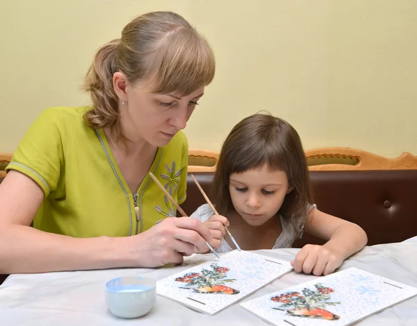 Молодая женщина с маленькой дочерью рисует краской кормушку для птиц — стоковое фото
