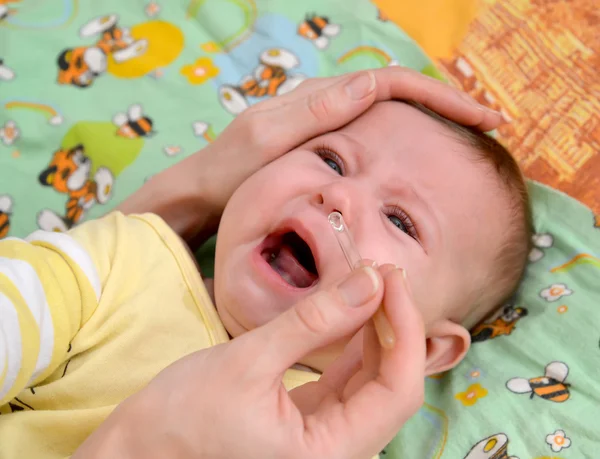 Die Frau gräbt die Tropfen in der Nase dem kranken weinenden Baby ein. Behandlung — Stockfoto