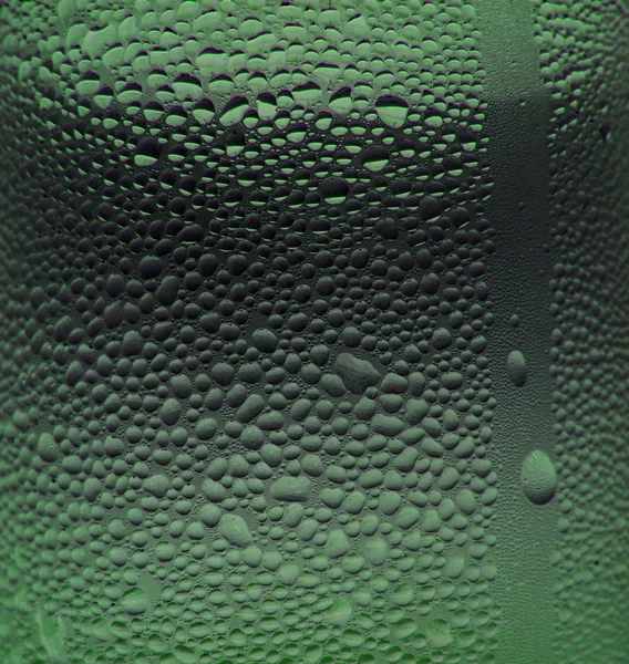 Vattendroppar på glaset med en färgad bakgrund. Droppar vatten. — Stockfoto