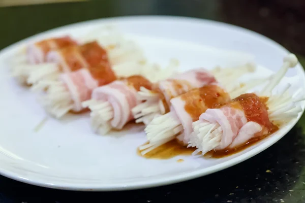 Raw bacon wrapped with needle mushroom — Stock Photo, Image