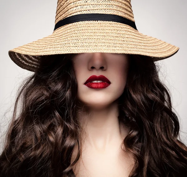 Glamoureuze portret van een brunette in een stro hoed. Rechtenvrije Stockafbeeldingen