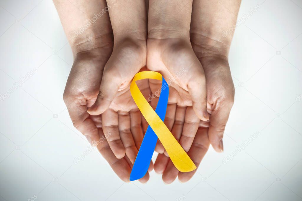 Adult and child hands holding blue and yellow ribbon shaped paper, Down syndrome awareness , World down syndrome day