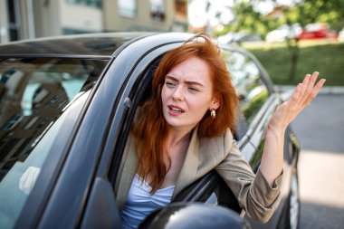 Sinirli Kızıl Saçlı Kadın Sürücü Trafikte Sıkıştı, Öfkeli Kadın Sürücü Yol Öfkesiyle, Stresli Kızıl Kadın Araba Penceresinden Dışarı Çıkma, Duygusal Ulaşım Konsepti.