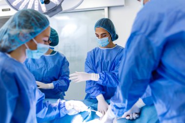 Modern Hastane Ameliyat Odasında Parlak Cerrahi Işıkları ile Kompleks Cerrahlar Yapıyor; Yoğun Bakımda Çalışan Sağlık Profesyonelleri