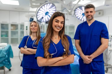 Başarılı Sağlık Ekibi Mavi Üniformalı Profesyoneller Modern Hastane Ameliyat Odası 'nda Parlak Cerrahi Işıklar ve Tıbbi Malzemeler ile Karşılaşan Silahlarla Bekliyorlar