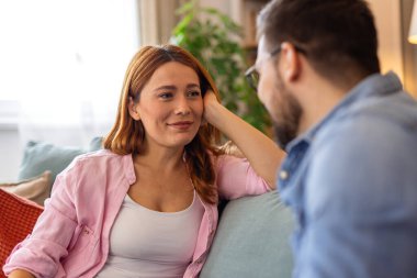 Evdeki koltukta otururken Sevgiyle Partnerine Bakan Güzel Genç Kadın. Mutlu çift sohbet ediyor ve sıcak bir oturma odasında birlikte vakit geçiriyor..