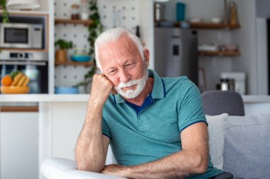 Kanepede oturan üzgün yaşlı adam evde yalnız ya da depresif hissediyor. Sağlık sorunları veya finansal borçlar hakkında endişelenen yaşlı bir erkek. Emeklilerle ruh sağlığı ve yaşlanma kavramı.